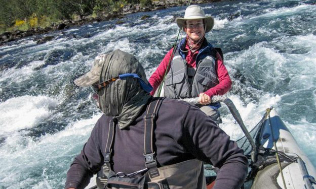A fishing guide deftly maneuvers a cataraft down a rapids into perfect position to fish the pool below it while an angler seems to be enjoying the ride.